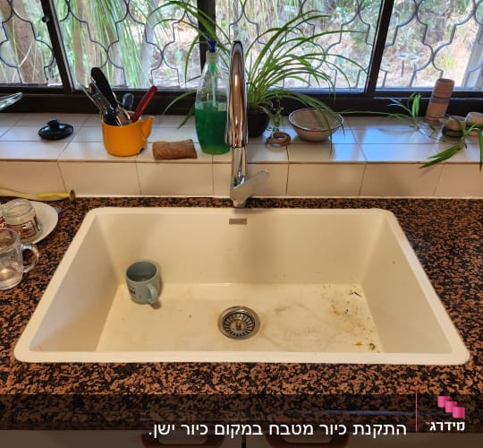 כיור מטבח עם כלים על משטח שיש